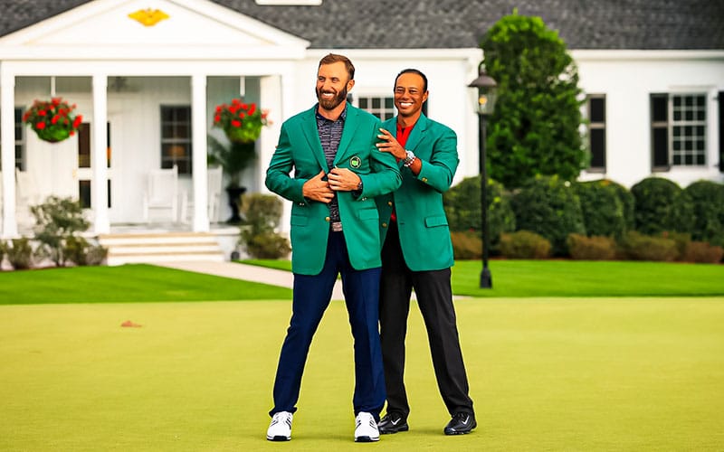 Tiger Woods puts the green jacket on Dustin Johnson after he won the Masters golf tournament at Augusta National Golf Club.